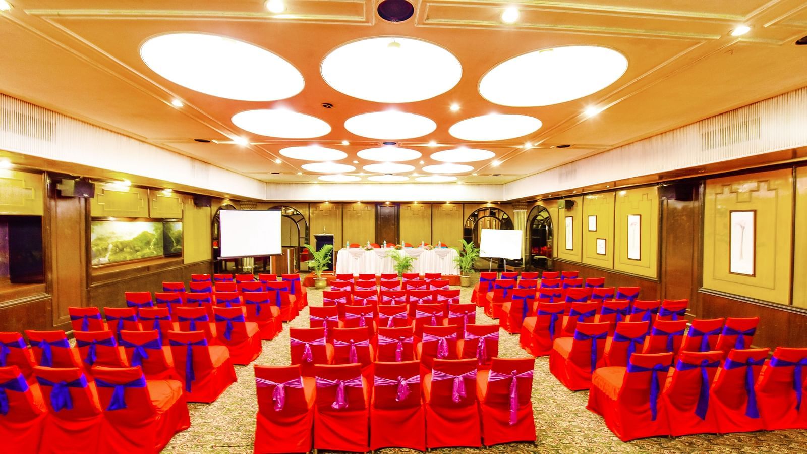 Image of a banquet hall with chairs arranged and a fancy lighting on the ceiling at Swosti Grand, Bhubaneswar