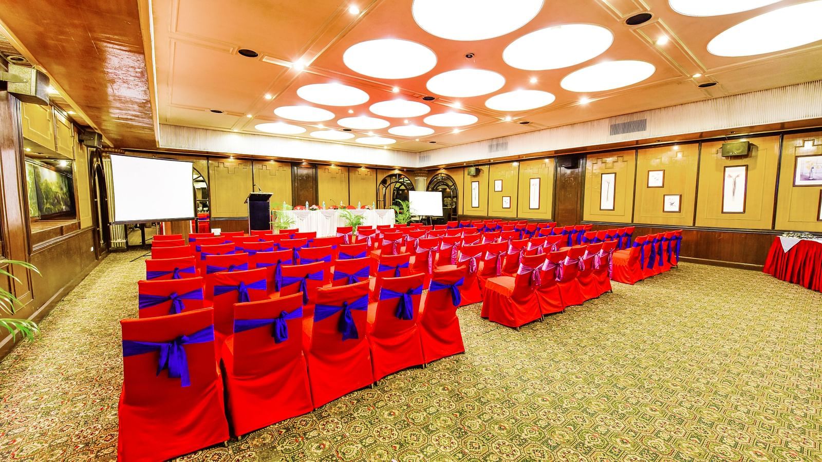 Back view of a banquet hall with chairs arranged and a fancy lighting on the ceiling at Swosti Grand, Bhubaneswar