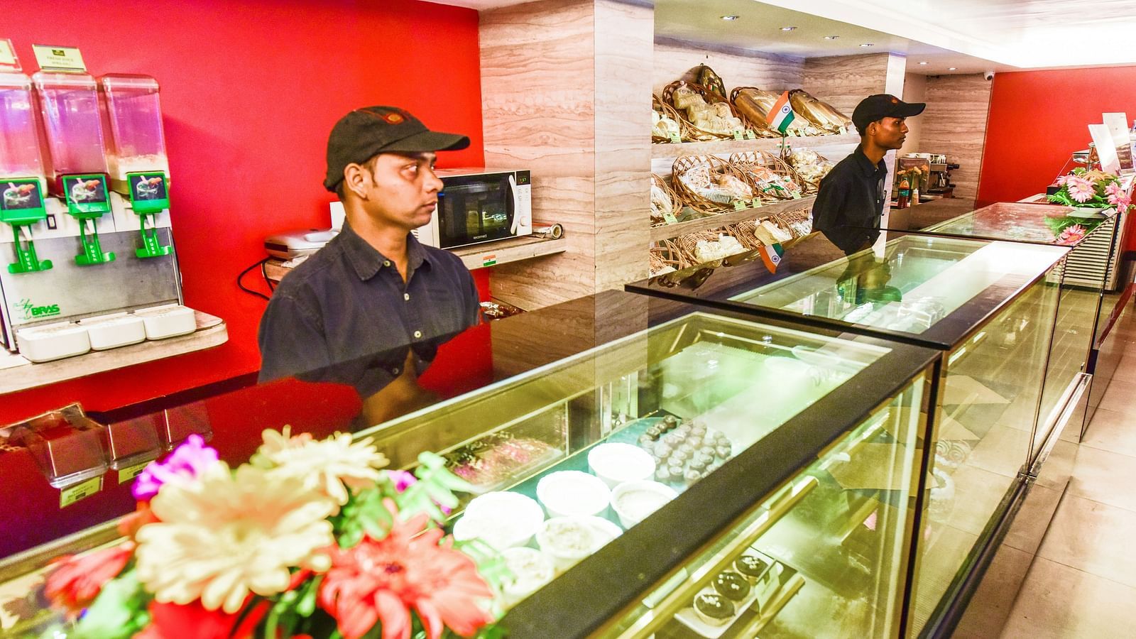 Close up image of Brown N Cream shop with pastries and two men waiting the shop at Swosti Grand, Bhubaneswar