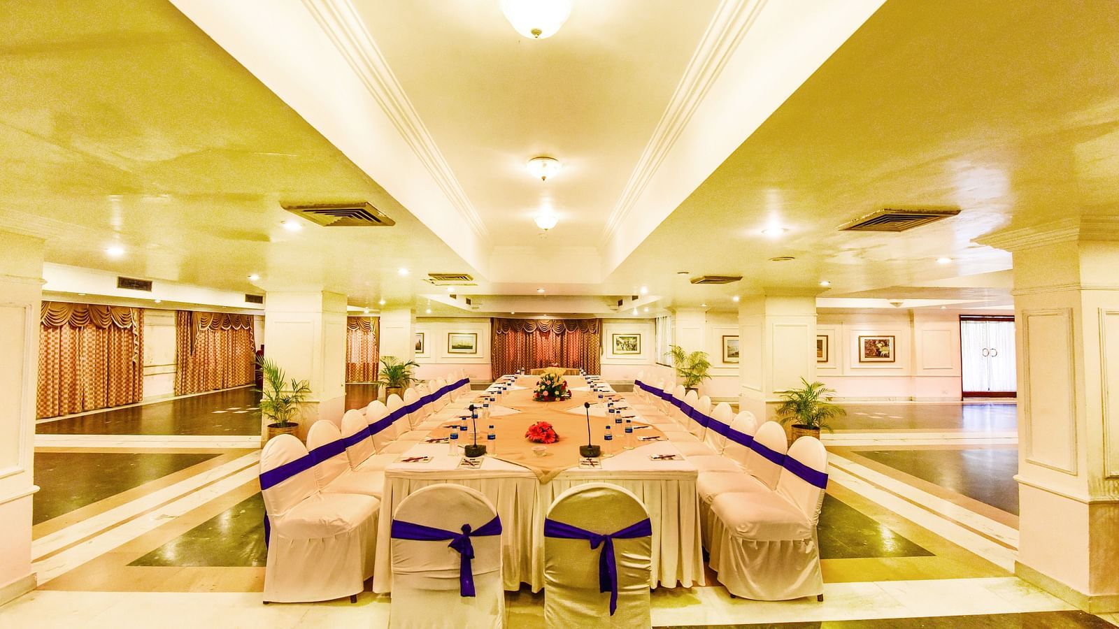 Well-lit banquet hall, with comprehensive decorations, ready to host a festive event.
