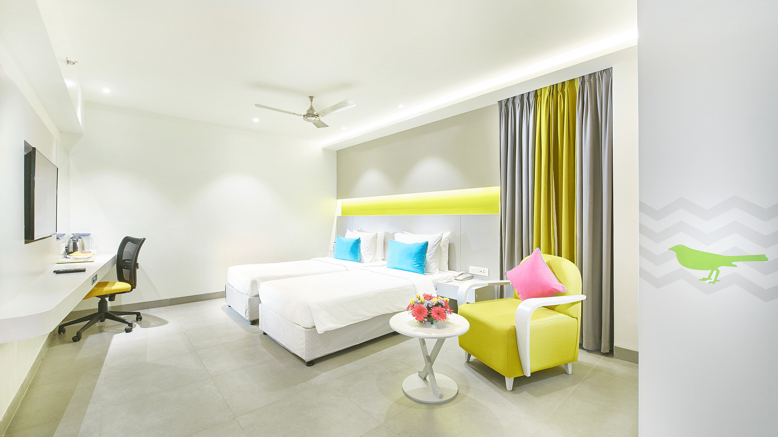 side view of a bedroom featuring a wall-mounted television and a ceiling fan at Zibe Salem by GRT Hotels 