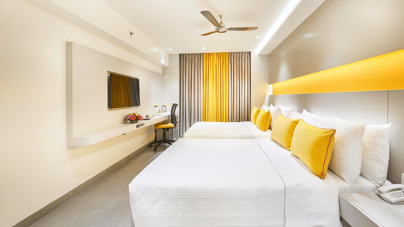 An image of a bedroom featuring a wall-mounted television and a ceiling fan  at Zibe Salem by GRT Hotels  