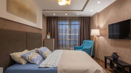 Cosy hotel room with large bed, soft lighting, modern decor, and a wall-mounted TV