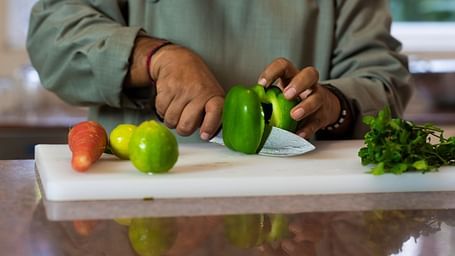 Image of a chef cutting vegetables on a chopping board.