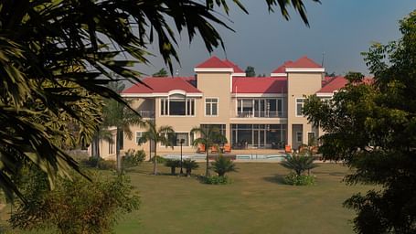 Facade view of BluSalzz Resort with garden and trees in the front.
