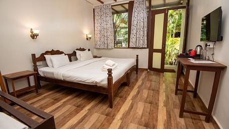 Spacious room with large bed, wooden furniture, and a wall-mounted TV at at De Soul Santé, Morjim.