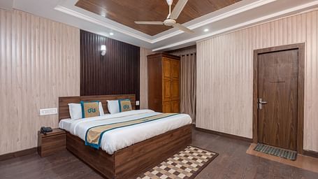 A wide angle shot of a king size bed in the a room with wooden flooring  | DLS Anupam Resort, Dharamshala
