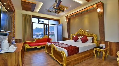A Luxury Room at DLS Dalhousie Valley Resort with a premium bed, a sofa and balcony.