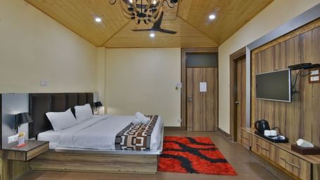 Family Suite at DLS Dalhousie Valley Resort with a king size bed, a table, chandelier and a TV. 