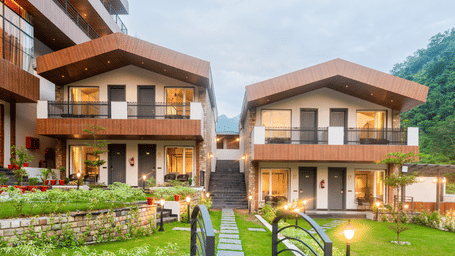Facade of DLS Divine River Resort and Spa surrounded by lush green gardens and lamp posts.