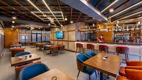 Interior of a Distil bar with wooden accents, blue chairs, and warm lighting labeled 'Distil Bar'