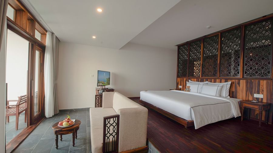 A hotel room with a balcony, plenty of amenities and a sofa facing towards the balcony - Alibu Resort Nha Trang