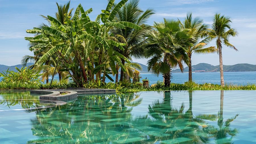A image of pool with some palm trees and a riverside view - Alibu Resort Nha Thrang