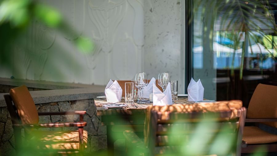 An outdoor sitting area with wooden chairs and tables- Alibu Resorts Nha Trang