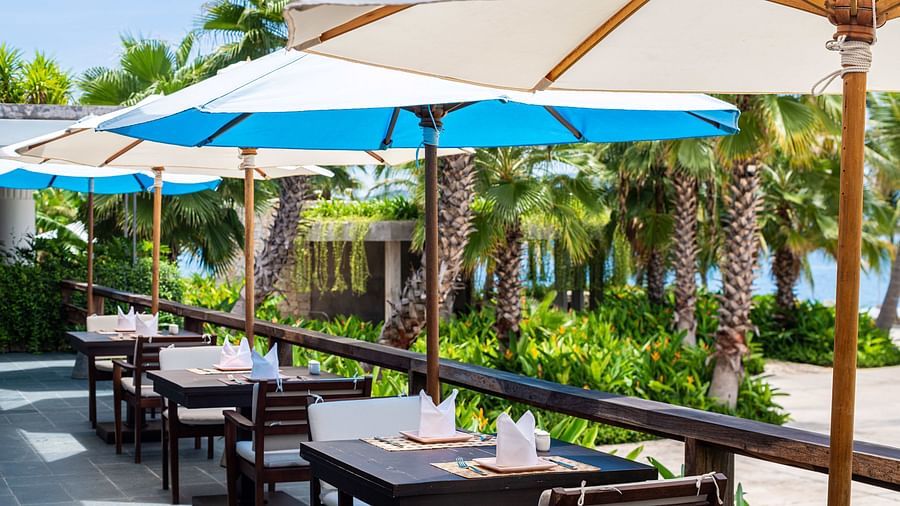 An outdoor sitting area with wooden chairs and tables - Alibu Resorts Nha Trang