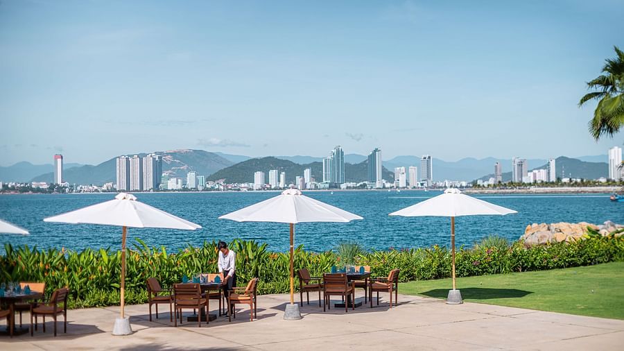 An image of a riverside with huge umbrellas and chairs underneath  - Alibu Resorts Nha Trang