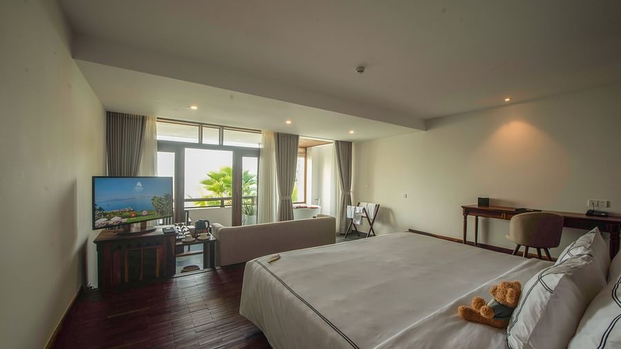 A room with a plush bed, a television, a work desk, a chair and a balcony with a view - Alibu Resort Nha Trang
