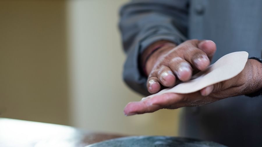 An image of a man making roti with his hands.