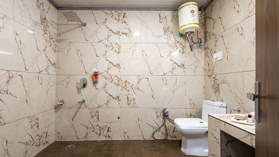 A side angle shot of the washroom featuring a commode and a geyser | DLS Anupam Resort, Dharamshala