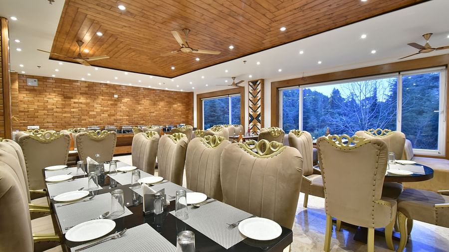 Dining area with comfortable chairs around tables at Rainbow Restaurant at DLS Ark Holiday Inn, Banikhet.