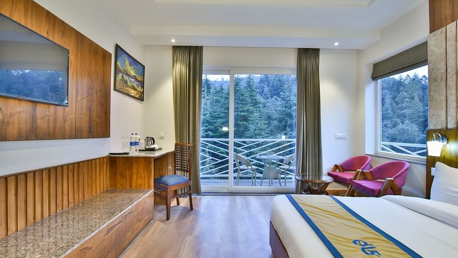 A view of the TV in front of the bed in Premium Room With Balcony at DLS Ark Holiday Inn, Banikhet.