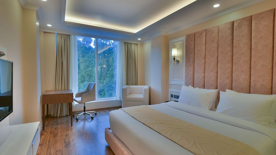 A clean and stylish bedroom featuring a large bed, a modern design, and large windows allowing plenty of natural light and beautiful mountain views.