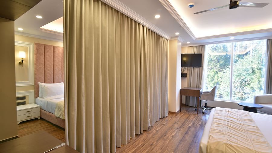 A spacious room with a curtain divider, featuring a comfortable bed, modern furniture, and large windows that provide a panoramic view of the surrounding landscape.