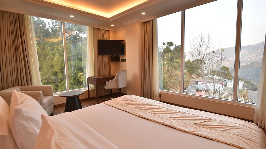 A well-lit bedroom with contemporary decor, large windows, and a comfortable bed. The space offers a calm, serene environment with views of the mountains.