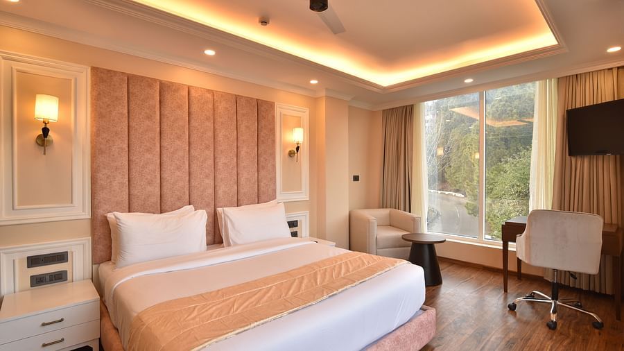 A modern bedroom with large windows that provide spectacular views of the surrounding mountains and lush greenery. The room features stylish furnishings and soft lighting.