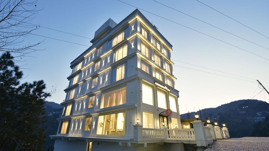 A stunning view of a modern hotel building at night, beautifully illuminated, with an elegant architectural design. The surrounding landscape adds to the serene atmosphere.