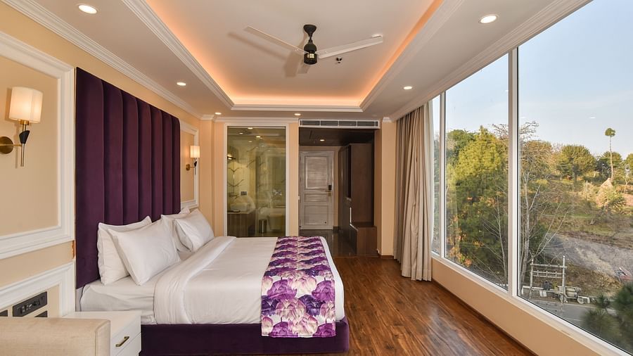  A well-designed bedroom with a comfortable bed, purple bedding, and large windows that open to views of the beautiful mountain landscape.