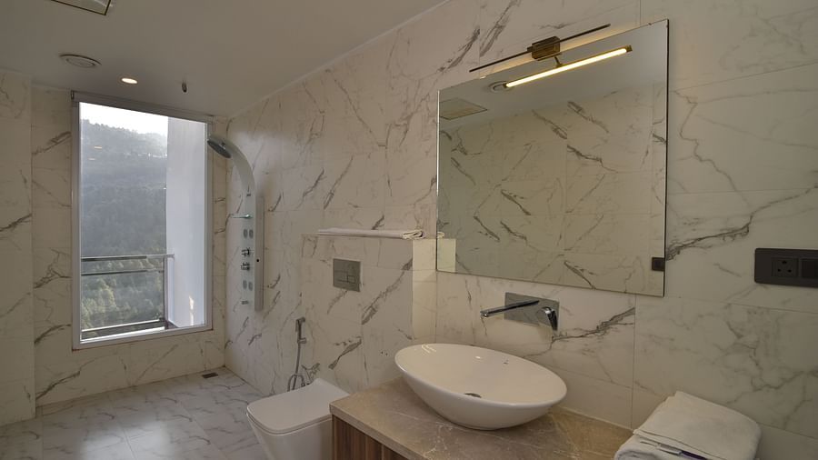 A sleek and modern bathroom with a marble countertop, a round sink, and contemporary fixtures. Large windows allow natural light to illuminate the space.