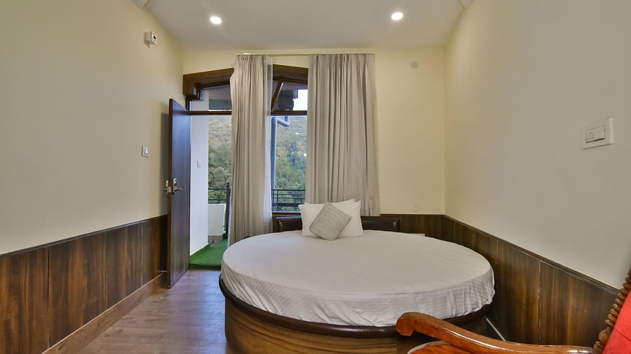 A Deluxe Room at DLS Dalhousie Valley Resort with a round king size bed and a balcony 