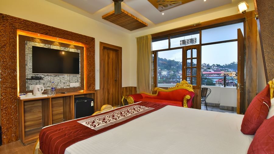 A Luxury Room at DLS Dalhousie  Valley Resort with a premium bed, a sofa, TV and balcony.