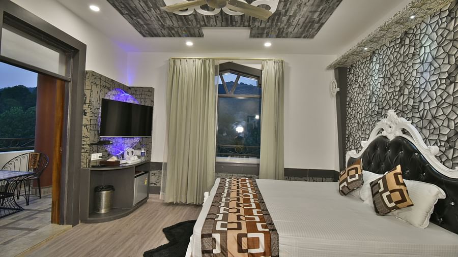 A Luxury Room at DLS Dalhousie  Valley Resort with a premium bed, a sofa, TV and balcony.