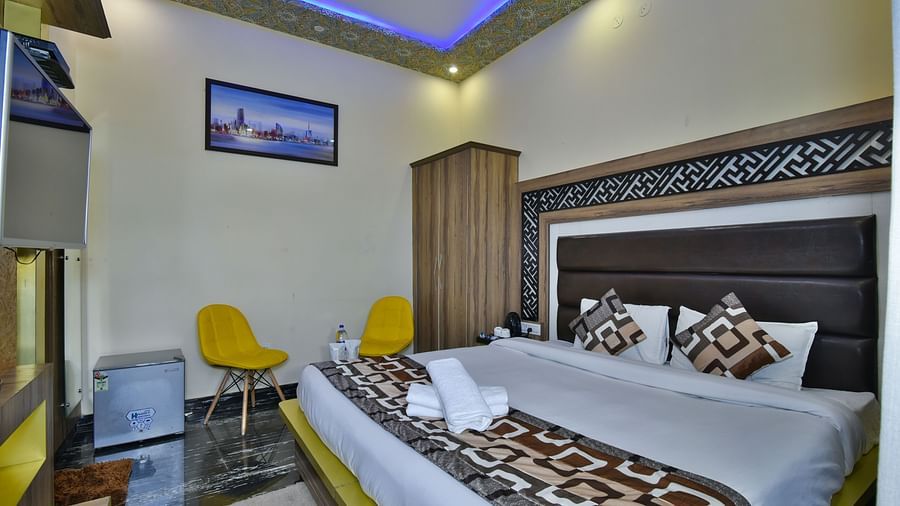 A Deluxe Room at DLS Dalhousie Valley Resort with a  king size bed and two yellow chairs