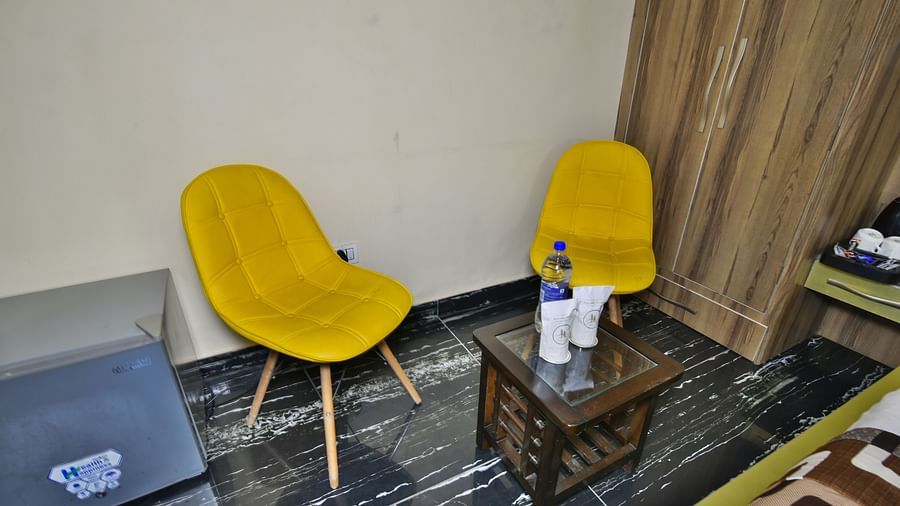 Sitting area of a Deluxe Room at DLS Dalhousie Valley Resort with yellow chairs and a table.