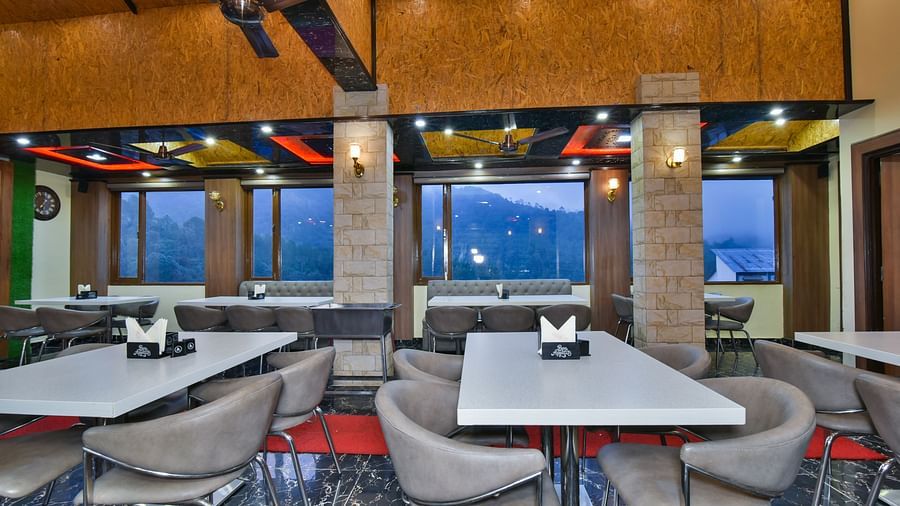 Restaurant at DLS Dalhousie Valley Resort with chairs, tables, ambient lighting and serene views