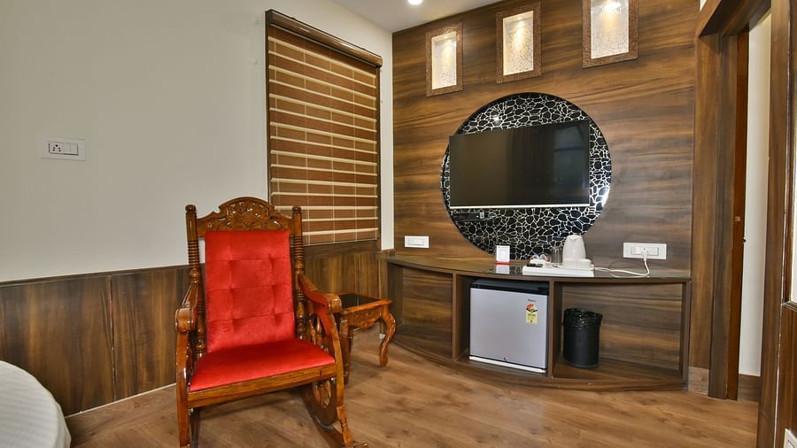 Sitting area of a Deluxe Room at DLS Dalhousie Valley Resort with a red chair, mirror and a table.