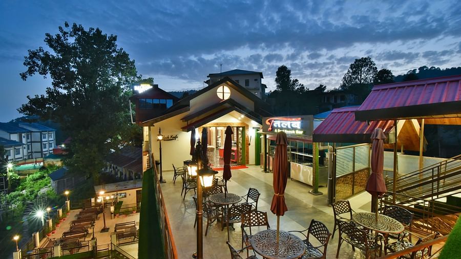 Facade image with warm lighting of DLS Dalhousie Valley Resort taken at night  featuring chairs and tables.