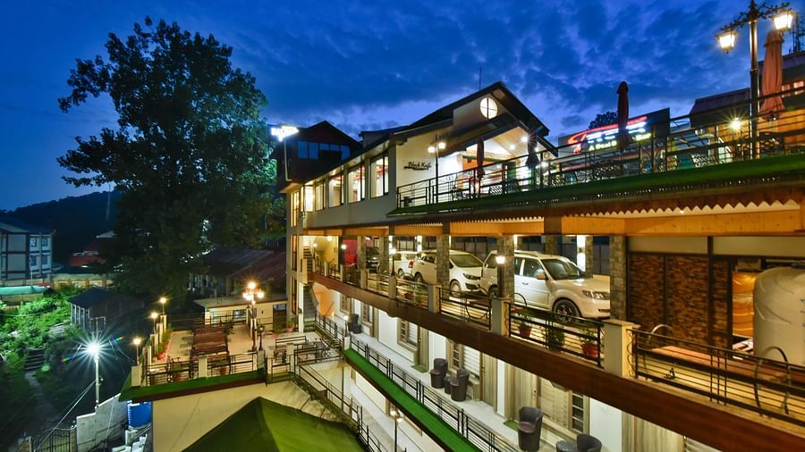 Facade image of DLS Dalhousie Valley Resort taken at night with warm lighting featuring parking area as well.