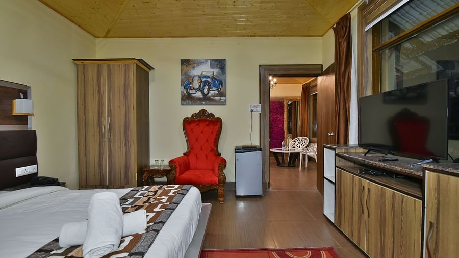 Family Suite at DLS Dalhousie Valley Resort with a king size bed, a table, chair and a door. 