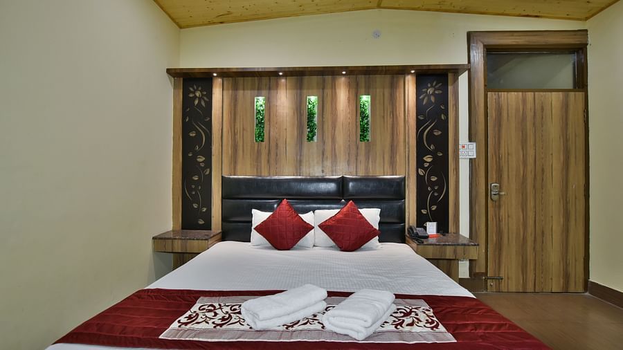 Family Suite at DLS Dalhousie Valley Resort with a king size bed and towels kept on bed.