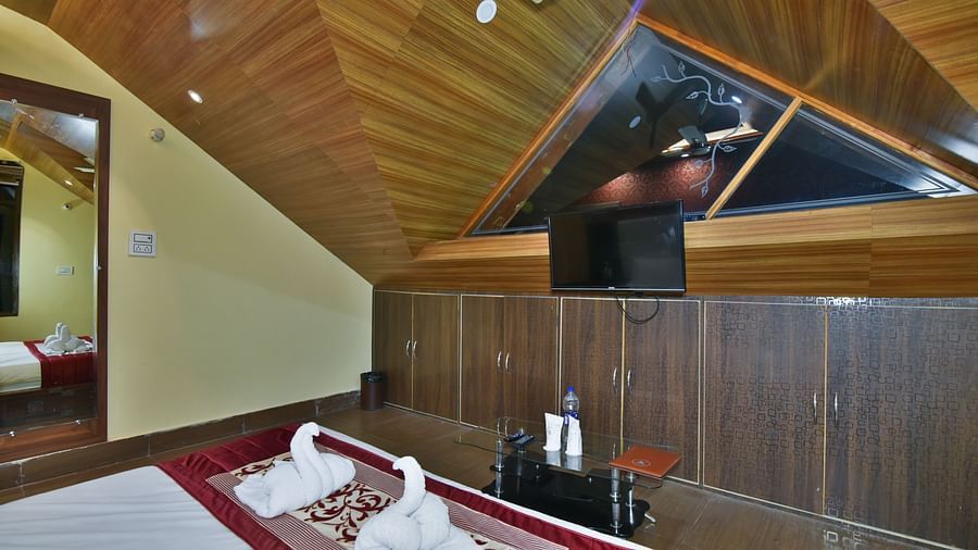 A Deluxe Room at DLS Dalhousie Valley Resort with a  king size bed, TV and a mirror.
