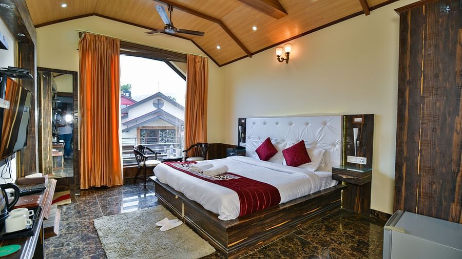A Deluxe Room at DLS Dalhousie Valley Resort with a  king size bed, TV and a balcony 