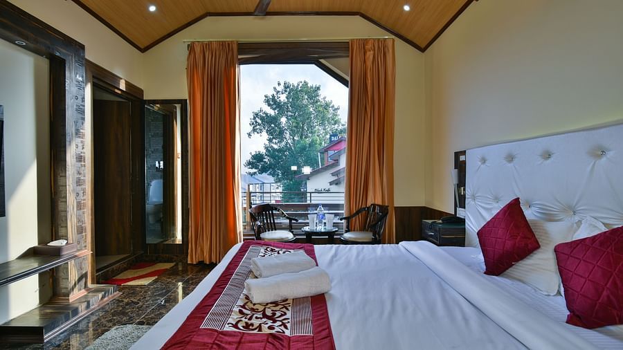 Overview of a Deluxe Room at DLS Dalhousie Valley Resort with a  king size bed and a balcony 