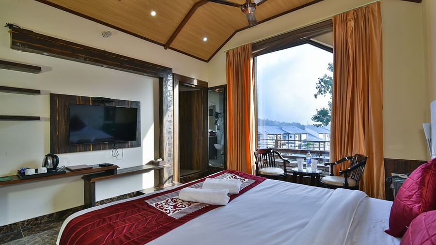 A Deluxe Room at DLS Dalhousie Valley Resort with a  king size bed and a balcony.