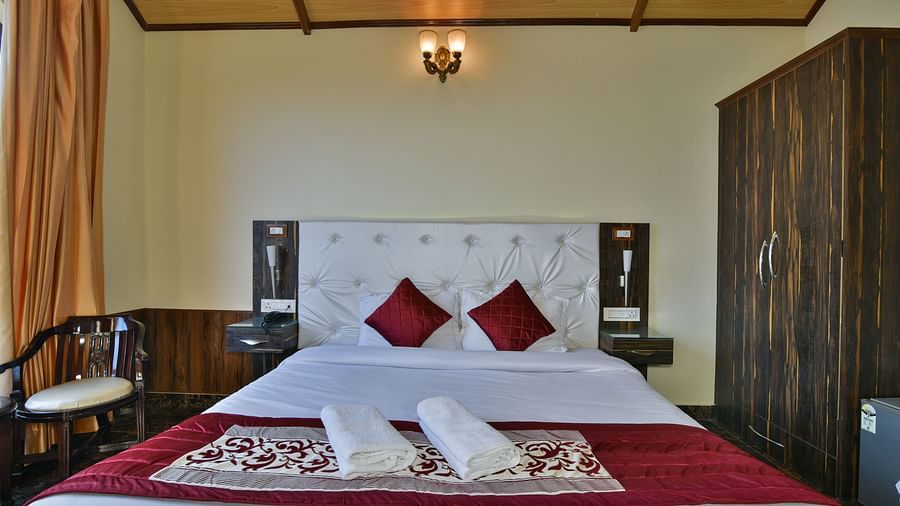 A Deluxe Room at DLS Dalhousie Valley Resort with a king size bed, a chair and ambient lighting. 