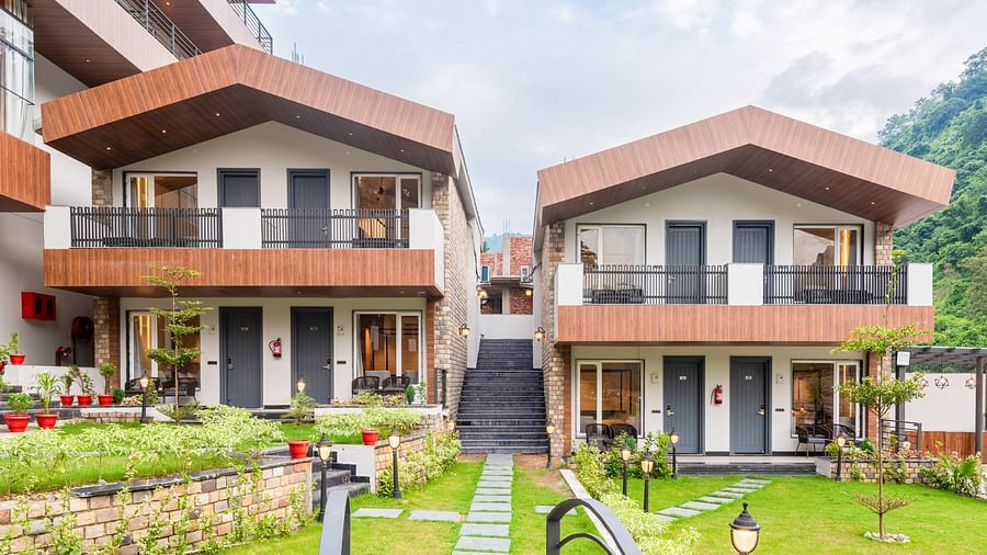 Facade of DLS Divine River Resort and Spa surrounded by lush green gardens and lamp posts.