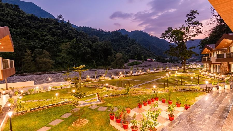 Garden area at DLS Divine River Resort and Spa featuring lush green grass and flower pots.